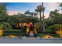 Stately home with a red door surrounded by mature trees and manicured landscaping, warmly lit at dusk at 208 Sumter Ave, Summerville, SC 29483