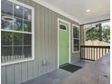 View of a charming porch featuring gray tiling, a bright green door, and lots of natural light at 227 Grace St, Walterboro, SC 29488