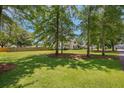 Backyard view featuring mature trees, a manicured lawn, and a charming home at 309 Pinopolis Park Dr, Moncks Corner, SC 29461
