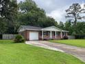 Inviting front yard with a lush lawn and a long driveway leading to an attached garage at 352 Oxford Rd, Ladson, SC 29456