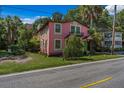 Two-story pink house with a balcony and green trim, nestled among palm trees and greenery at 509 E Ashley Ave, Folly Beach, SC 29439