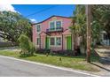 Quaint two-story pink home with a balcony and vibrant green doors, surrounded by trees at 509 E Ashley Ave, Folly Beach, SC 29439