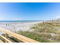 Beach and dunes view with wooden railing, showcasing a sunny day at the ocean at 509 W Ashley Ave, Folly Beach, SC 29439