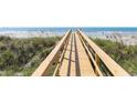 Wooden walkway leading to the sandy beach and ocean with grasses on either side at 509 W Ashley Ave, Folly Beach, SC 29439