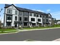 Modern new townhomes with covered entryways, black trim, and manicured front lawns at 556 Scholar Way, Summerville, SC 29486