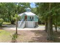 Inviting exterior showcasing a charming light blue coastal home with a white roof, and a spacious yard with mature trees at 16 Oakwood Ln, Edisto Island, SC 29438