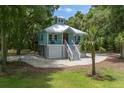 Picturesque exterior featuring a light blue coastal home with an elevated design, complemented by lush landscaping and gravel driveway at 16 Oakwood Ln, Edisto Island, SC 29438