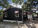 Modest single-story home featuring a black exterior, brick foundation, awning accents and mature trees at 2334 Kent Ave, North Charleston, SC 29405