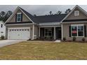 Single story home with taupe siding, covered porch, and a neatly kept green lawn at 265 Huguenot Trl, Huger, SC 29450