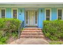 Charming entrance with brick steps, blue walls, white trim, and decorative sconces, with lush green shrubs at 312 Woodward Blvd, Summerville, SC 29483