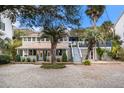 Charming two-story home featuring a welcoming front porch, lush landscaping, and a side staircase to a deck at 504 W Ashley Ave, Folly Beach, SC 29439