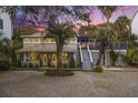 Charming two-story home featuring a welcoming front porch, lush landscaping, and a side staircase to a deck at 504 W Ashley Ave, Folly Beach, SC 29439