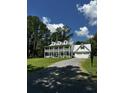 Two-story white farmhouse with a large lawn, gravel driveway and double garages at 5681 Captain Kidd Rd, Hollywood, SC 29449