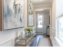 Inviting entryway featuring neutral walls, wood floors, modern console table with flowers and art at 754 Blue Iris Way, Summerville, SC 29486