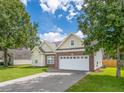 Inviting exterior of home with a two-car garage, brick accents, and well-maintained lawn at 7812 Spring Creek Rd, North Charleston, SC 29418
