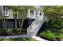 Elegant white staircase leading to a charming porch area, surrounded by lush greenery and manicured landscaping at 932 Middle St, Sullivans Island, SC 29482