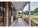 Covered front porch provides an airy view, featuring a comfortable bench and beautifully landscaped surroundings at 104 Jackson Rd, Ladson, SC 29456