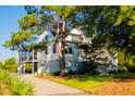 Stately two-story home with a gravel driveway and screened-in porch, surrounded by mature trees at 2312 Rushland Landing Rd, Johns Island, SC 29455