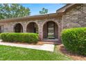 Close up of the front door with arched brick entryway and well-manicured shrubbery at 8116 Long Shadow Ln, North Charleston, SC 29406