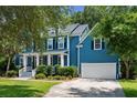 Charming blue two-story home featuring a well-manicured lawn, a columned porch and an attached two-car garage at 3574 Toomer Kiln Cir, Mount Pleasant, SC 29466