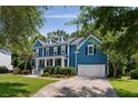 Charming blue two-story home featuring a well-manicured lawn, a columned porch and an attached two-car garage at 3574 Toomer Kiln Cir, Mount Pleasant, SC 29466