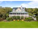 Elevated two-story home with metal roof, large front yard, and manicured landscaping at 377 Lofton Ct, McClellanville, SC 29458