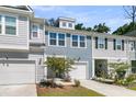 View of the townhome with a white garage door, manicured lawn, and a small tree in the front yard at 493 Trotters Ln, Moncks Corner, SC 29461