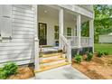 Inviting front porch with white columns and stairs, complemented by planters and manicured landscaping at 5710 Barbary Coast Rd, Hollywood, SC 29449