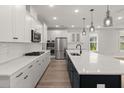 Modern kitchen features white cabinets, stainless steel appliances, a large island, and hardwood floors at 123 Leeward Lndg, Summerville, SC 29486