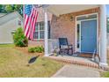 Inviting front porch featuring a rocking chair, patriotic flag, and a classic brick facade at 2404 Fulford Ct, Mount Pleasant, SC 29466