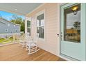 Inviting front porch featuring rocking chairs, light blue door, and view of the surrounding neighborhood at 325 Blowing Fresh Dr, Charleston, SC 29492
