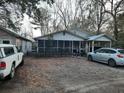 Front exterior of a home with large trees and a gravel driveway and a screened porch at 6385 Sc-162, Hollywood, SC 29449