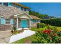 Beautiful brick home with colorful turquoise door/shutters, complemented by vibrant red roses in the front garden at 1369 Miles Dr, Charleston, SC 29407