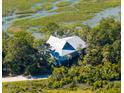 Aerial shot of the home showcasing its setting amongst trees with views of the marsh at 226 Old House Ln, Dewees Island, SC 29451