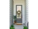 Inviting front entry with a gray door, seasonal wreath, and decorative plants at 3082 Emma Ln, Mount Pleasant, SC 29466