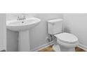 A minimalist bathroom featuring a pedestal sink and white toilet with wood-style flooring, offering a clean and functional space at 403 Cadbury Loop, Summerville, SC 29486