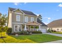 Charming two-story home with a well-manicured lawn, inviting front porch, and attached two-car garage at 404 Topcrest Ln, Moncks Corner, SC 29461