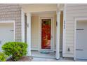 Close-up of townhome's red front door with address, surrounded by white columns and manicured shrubs at 4964 Hay Bale Ct, Summerville, SC 29485