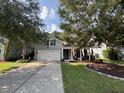 Lovely two-story home with gray siding, a two-car garage, and a welcoming front porch framed by mature trees at 5008 W W Liberty Meadows Dr, Summerville, SC 29485