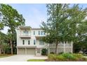 Charming three-story home with a two-car garage, well-kept lawn, and mature trees enhancing curb appeal at 55 Seagrass Ln, Isle of Palms, SC 29451