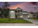 Beautiful home with a double porch, lush green lawn, and the colorful hues of the sunsetting sky at 7045 Stonecrop Ln, Johns Island, SC 29455