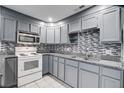 Well-lit kitchen features gray cabinets, stainless steel appliances, and a mosaic backsplash at 1112 Yeamans Hall Rd, Hanahan, SC 29410