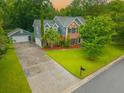 Aerial view of a two-story home with a detached garage, and long driveway surrounded by lush landscaping at 138 Shadowmoss Pkwy, Charleston, SC 29414