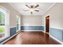 Sun-filled living room featuring fresh paint, wainscotting, hardwood flooring, and updated light fixture at 138 Shadowmoss Pkwy, Charleston, SC 29414