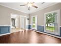 Bright living room with wainscotting, hardwood flooring, fresh paint, and large windows providing natural light at 138 Shadowmoss Pkwy, Charleston, SC 29414