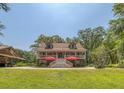Charming two-story home boasts a full front porch, red umbrellas, and a manicured lawn at 150 Riverbend Ln, Ridgeville, SC 29472