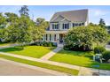 Attractive two-story house featuring a verdant lawn, flowering trees, and a paved walkway at 173 Silver Cypress Cir, Summerville, SC 29485