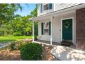 Inviting front porch with green door, lush landscaping, and views of a serene backyard pond at 190 Darcy Ave, Goose Creek, SC 29445