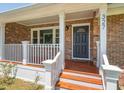 Inviting front porch with brick facade, white columns, and wood steps, leading to the front door at 327 Mcclain St, Charleston, SC 29407