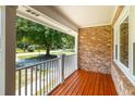 Covered porch featuring stained wood flooring, white railings, and brick walls with a view of the yard at 327 Mcclain St, Charleston, SC 29407